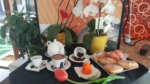 un tavolo con un vassoio di pasticcini e tazze di caffè di La Piazzetta Guest House a Olbia
