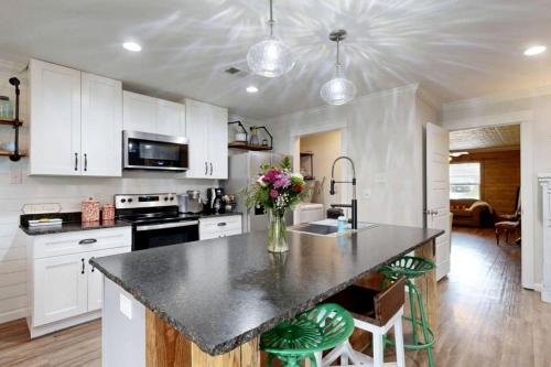 a kitchen with white cabinets and a black counter top at Modern Farmhouse Escape with Patio & Fire Pit in Bryan, Texas in Bryan