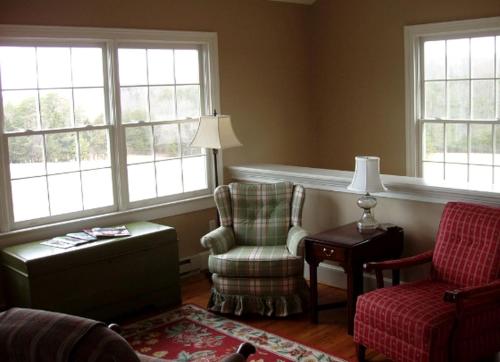 a living room with a chair and a lamp and windows at Two-Bedroom, One Bathroom Cottage on 250-Acre Cattle Farm for Getaway near Richmond, Virginia in Howardsville
