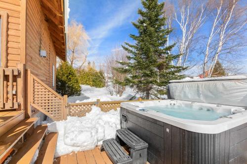 un jacuzzi en una terraza en la nieve en Spa Pool table Mountain view - Martine-54, en Petite-Rivière-Saint-François