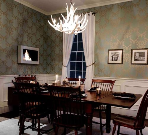 una sala da pranzo con tavolo, sedie e lampadario di Gorgeous Green Mountain Retreat for a Family Vacation in Vermont a Mount Holly