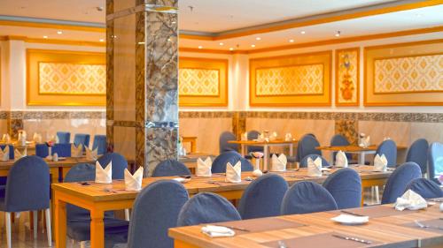 a dining room with wooden tables and blue chairs at Casa Diora Hotel Al Naseem in Jeddah