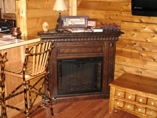 Una chimenea en una habitación con una silla y una mesa en Rustic Log Cabin For a Group Getaway near Lake Cumberland in Kentucky, en Liberty