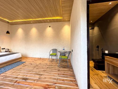 a bedroom with a bed and a table and two chairs at Anupraas Resort in Lansdowne