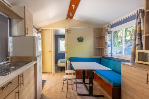 a small kitchen with a table and a blue bench at Les Rives d’Auzon Mobil-home 6 pers in Lavilledieu