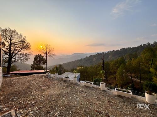 a sunset on top of a hill with a view at Anupraas Resort in Lansdowne
