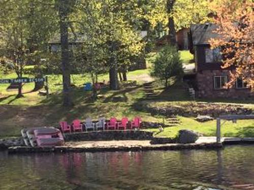 a group of chairs and a house next to a lake at Calming Cabin Rental with Lake Views near Nicolet National Forest, Wisconsin in New Post