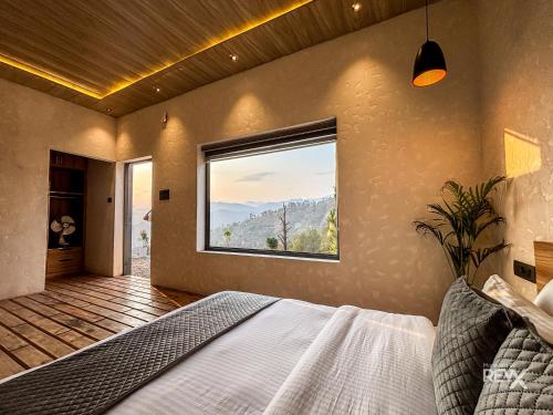 a bedroom with a bed and a large window at Anupraas Resort in Lansdowne