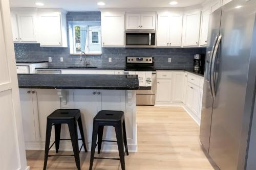 une cuisine avec des armoires blanches et un réfrigérateur dans l'établissement Stunning Modern Lakehouse with Private Boat Dock in Norwood, North Carolina, à Norwood