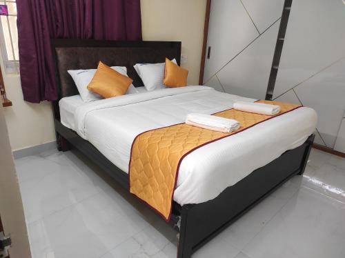 a bedroom with a bed with orange and white pillows at Hotel O Pranavam Home Stay in Tirupati