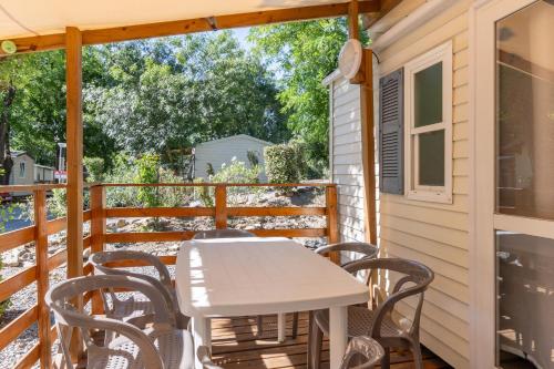 a table and chairs on the deck of a cabin at Les Rives d’Auzon Mobil-home 6 pers in Lavilledieu