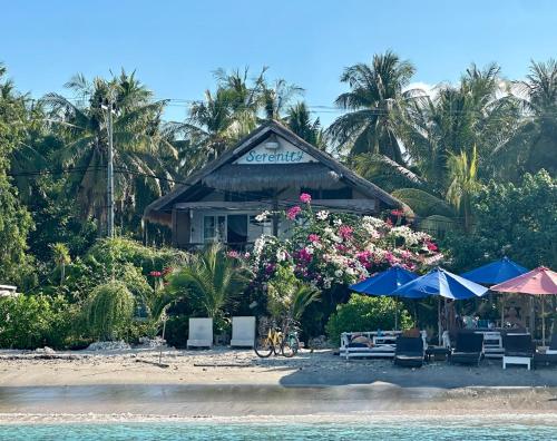 ein Gebäude am Strand mit Stühlen und Sonnenschirmen in der Unterkunft Serenity Luxurious Beachfront Villa & Spa with private Infinity Pool, 8 Guests in Gili Air