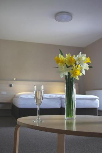 a table with a vase of flowers and a wine glass at Wellness hotel Sauna in Malá Morávka