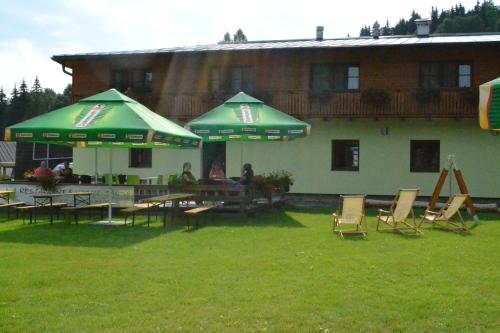 a group of chairs and tables with umbrellas in front of a building at Wellness hotel Sauna in Malá Morávka