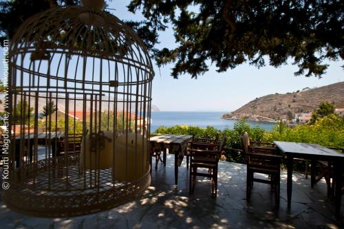 a bird cage with tables and chairs and the ocean at Niriides Hotel Apartments in Symi