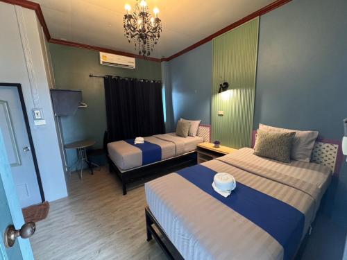una camera d'albergo con due letti e un lampadario a braccio di Paksina Hotel a Narathiwat