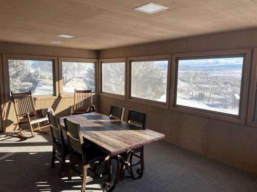 a room with a wooden table and chairs and windows at Amazing Retreat Ideal for Families or Groups in Saratoga, Wyoming in Encampment