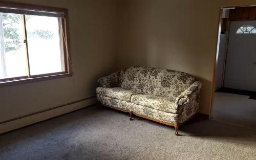 a couch in a corner of a room with a window at Rustic Cabin with a Picnic Table and Barbecue on Somo Lake, Wisconsin in Tomahawk