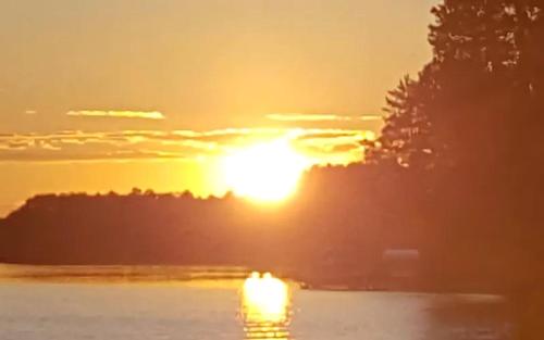 a sunset over a body of water with the sun setting at Rustic Cabin with a Picnic Table and Barbecue on Somo Lake, Wisconsin in Tomahawk