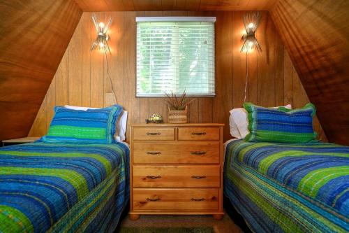 a bedroom with two beds and a dresser and a window at Wonderful A frame Nestled Amidst Trees in Otter Rock, Oregon in Otter Rock