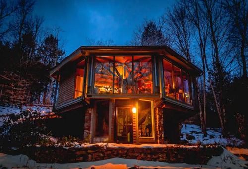 a glass house with a lot of windows at night at Imaginative Octogonal Glass Treehouse on Seven Private Acres near Great Barrington, MA in Otis