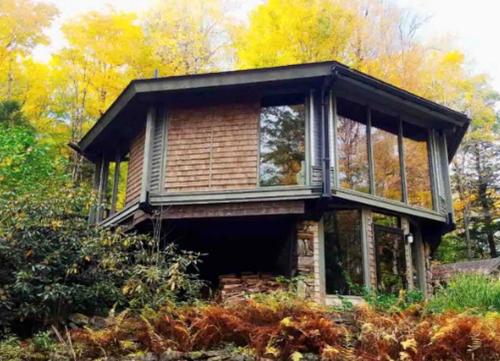 a house with windows on top of a field at Imaginative Octogonal Glass Treehouse on Seven Private Acres near Great Barrington, MA in Otis