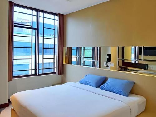 una camera da letto con un grande letto bianco con cuscini blu di MP Hotel Kelapa Gading a Giacarta