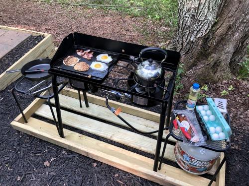 a grill on a wooden table with food on it at Luxurious Safari Tent in Cooperstown, NY - Perfect Glamping Spot for a Romantic Getaway in Cooperstown