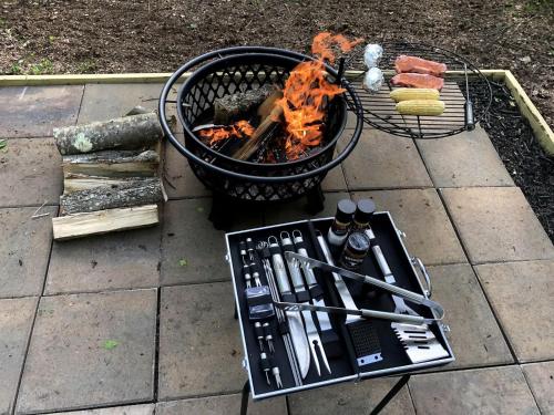 a grill with tongs next to a grill with food at Luxurious Safari Tent in Cooperstown, NY - Perfect Glamping Spot for a Romantic Getaway in Cooperstown