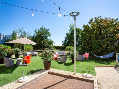 a garden with chairs and tables and an umbrella at Novotel Bourges in Bourges