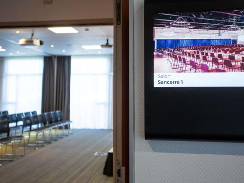an empty room with chairs and a projection screen at Novotel Bourges in Bourges