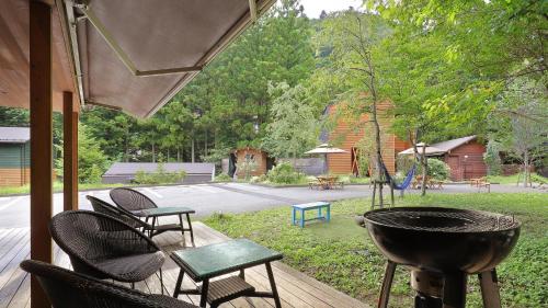 a grill on a deck with chairs and a playground at Onsen Glamping ShimaBlue in Nakanojo