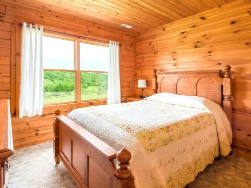 ein Schlafzimmer mit einem Bett und einem großen Fenster in der Unterkunft Gorgeous and Spacious Cabin Rental for a Group Vacation near Hocking Hills State Park, Ohio in Cedar Grove
