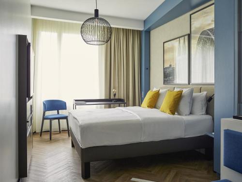 a bedroom with a large bed with yellow pillows at Hotel Mondial am Dom Cologne MGallery in Cologne