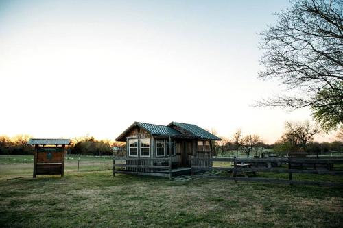 a small wooden cabin in a field with a fence at Rustic Tiny House Rental for Weekend Getaways from Dallas in Wilmer