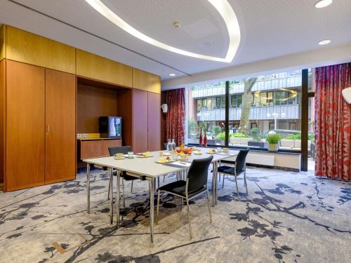 a dining room with a table and chairs and a large window at Hotel Mondial am Dom Cologne MGallery in Cologne