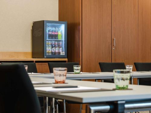 a room with tables and chairs with a drink cooler at Hotel Mondial am Dom Cologne MGallery in Cologne