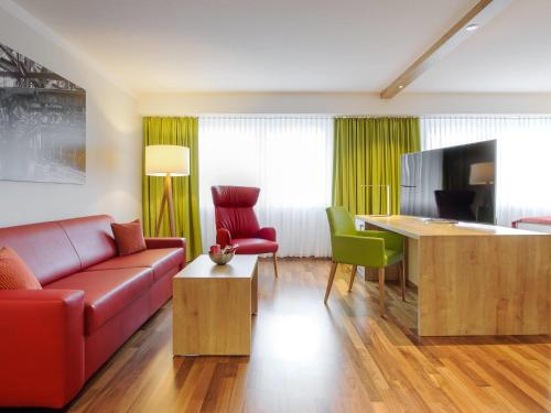 a living room with a couch and a table at Mercure Hotel Saarbrücken City in Saarbrücken