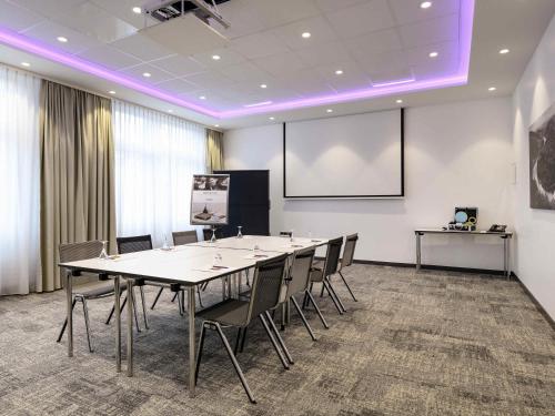 a conference room with a long table and chairs at Mercure Hotel Saarbrücken City in Saarbrücken