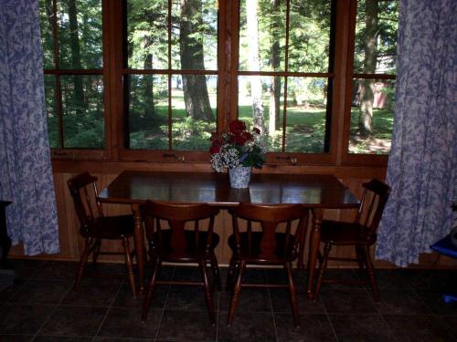 un tavolo da pranzo con sedie e un vaso di fiori di Cozy Cottage Rental with Lovely Beach Views on Halfmoon Lake, New Hampshire a New Durham