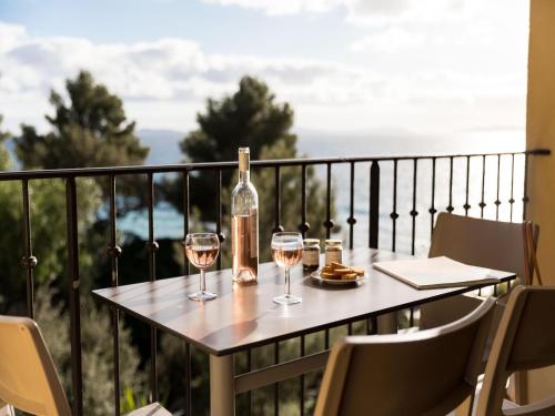 a table with two glasses of wine on a balcony at 2-room holiday flat with sea view in Residence du Bailli, Rayol-Canadel-sur-Mer in Rayol-Canadel-sur-Mer