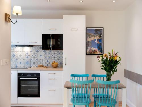 a kitchen with white cabinets and blue chairs at 2-room holiday flat with sea view in Residence du Bailli, Rayol-Canadel-sur-Mer in Rayol-Canadel-sur-Mer