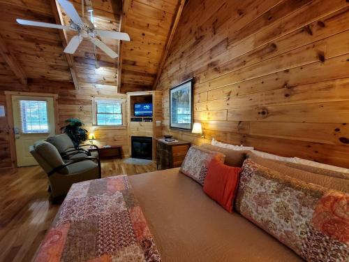 a living room with a bed and a ceiling fan at Peaceful Riverside Cabin Retreat Near New River, Virginia in Galax