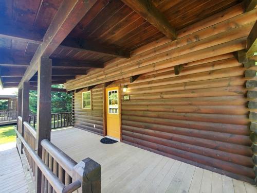 a wooden porch of a cabin with a yellow door at Peaceful Riverside Cabin Retreat Near New River, Virginia in Galax