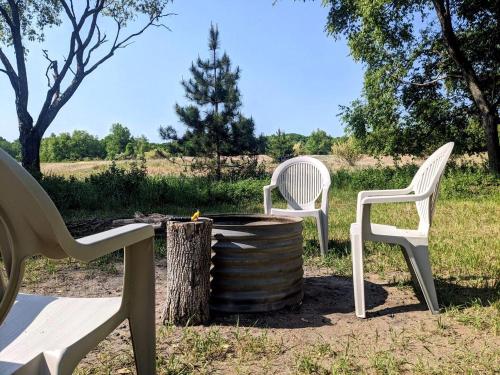 two white chairs sitting next to a fire pit at Secluded Off-Grid Yurt with Forest Views Near Trails in Sears, Michigan in Sears