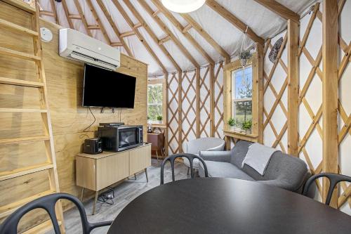 a room with a table and chairs and a tv at Secluded Off-Grid Yurt with Forest Views Near Trails in Sears, Michigan in Sears