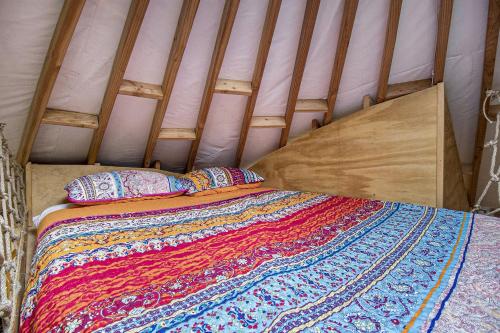 a bed in a tent with a blanket and pillows at Secluded Off-Grid Yurt with Forest Views Near Trails in Sears, Michigan in Sears