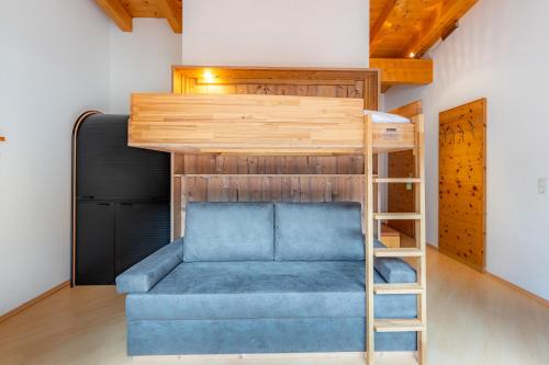 a loft bed with a blue couch in a room at Försterhaus & Haus Andrea in Mayrhofen