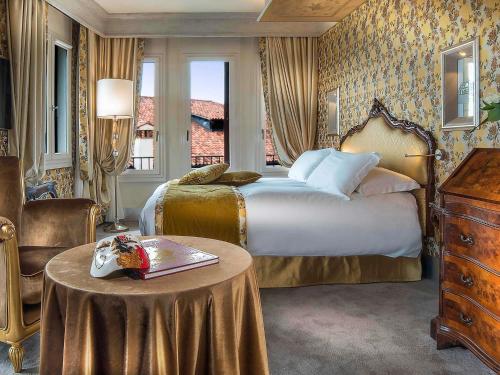 a bedroom with a bed and a table in a room at Papadopoli Hotel Venezia - MGallery Collection in Venice