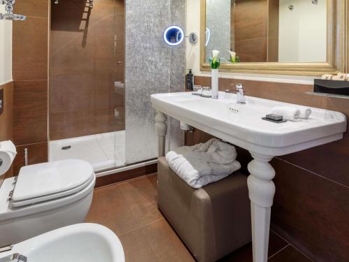 a bathroom with a sink and a toilet and a shower at Papadopoli Hotel Venezia - MGallery Collection in Venice